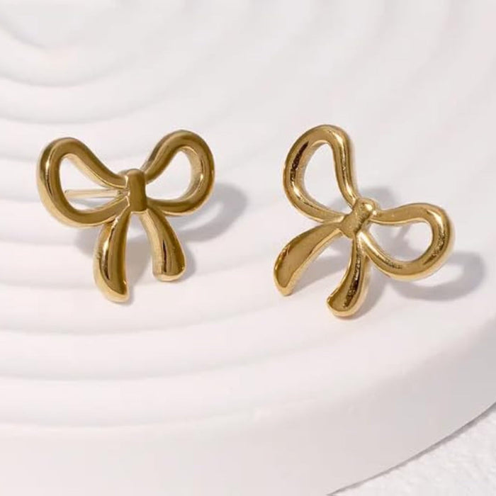 Gold bow stud earrings on white surface