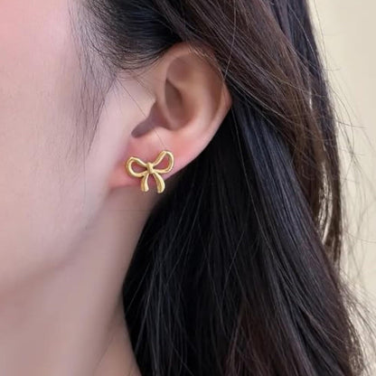 Gold bow stud earring worn on ear